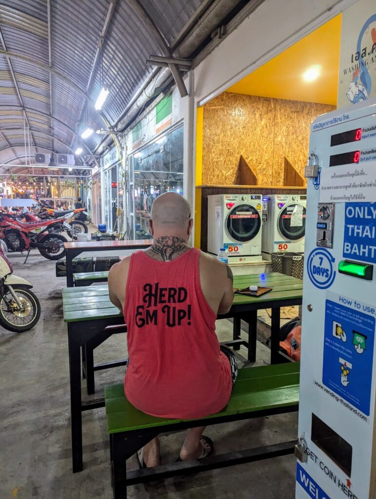 Digital Nomad sat outside laundrette in Thailand creating a website.